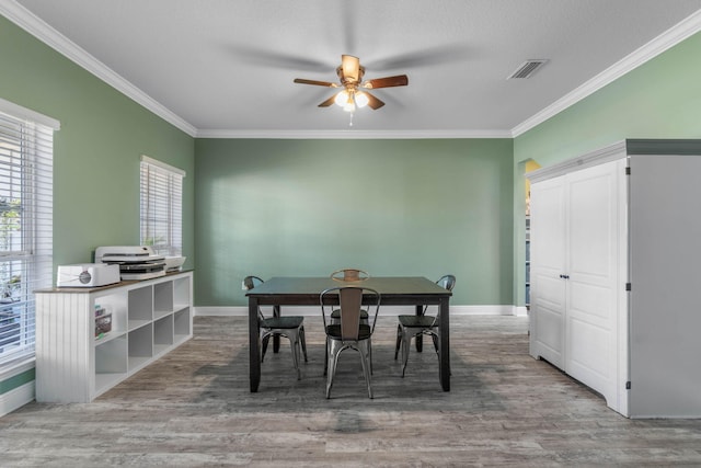 dining space with ornamental molding, wood-type flooring, and ceiling fan