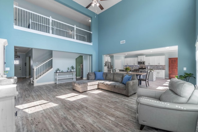 living room with hardwood / wood-style floors, a high ceiling, and ceiling fan