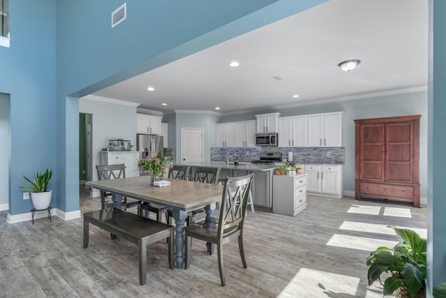 dining area featuring ornamental molding, sink, and light wood-type flooring