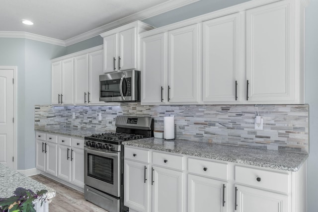 kitchen with white cabinetry, stainless steel appliances, ornamental molding, and decorative backsplash