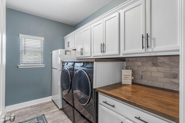 washroom featuring light hardwood / wood-style flooring, cabinets, and separate washer and dryer