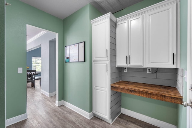 hallway with crown molding and light hardwood / wood-style flooring