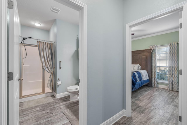 bathroom with toilet, hardwood / wood-style floors, walk in shower, and ornamental molding