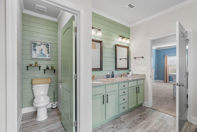 bathroom featuring hardwood / wood-style flooring, toilet, wood walls, vanity, and crown molding