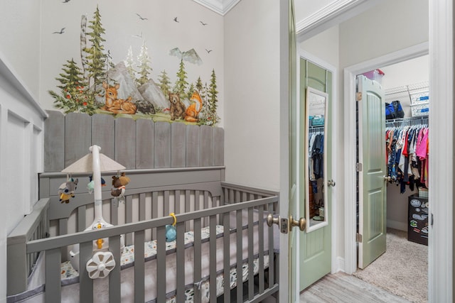 carpeted bedroom with ornamental molding and a nursery area