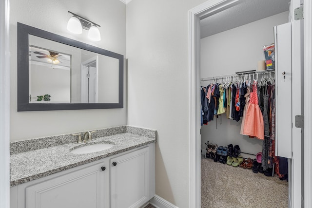 bathroom featuring vanity, ceiling fan, and a textured ceiling