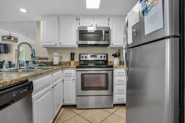 kitchen featuring appliances with stainless steel finishes, light tile patterned floors, white cabinetry, and sink