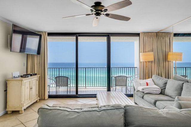 living room with ceiling fan, expansive windows, a water view, and light tile patterned floors