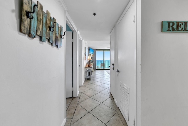 hallway with visible vents, light tile patterned flooring, and expansive windows