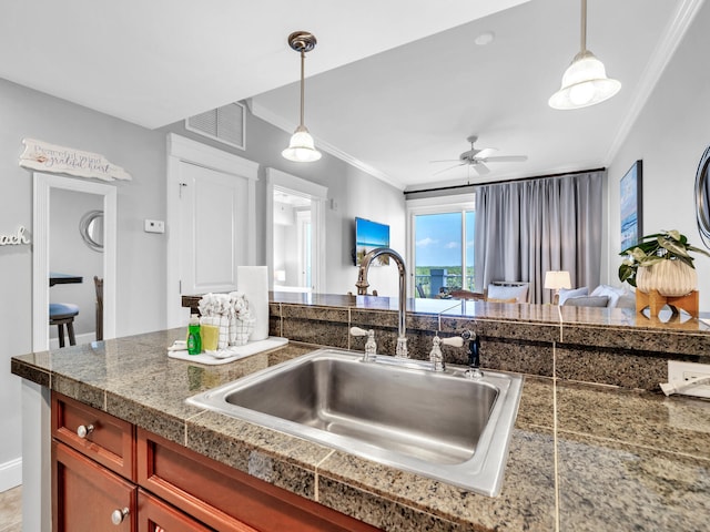 kitchen with hanging light fixtures, ornamental molding, sink, and ceiling fan