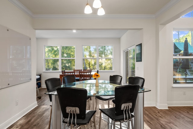 dining space featuring dark wood-type flooring, ornamental molding, and an inviting chandelier