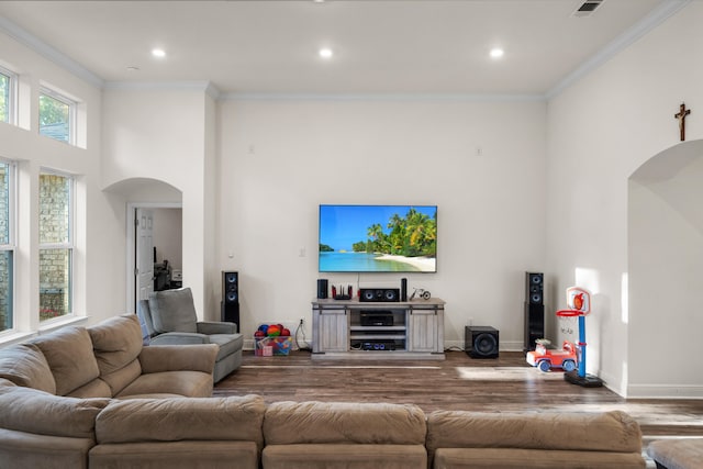 living room featuring ornamental molding, a towering ceiling, and hardwood / wood-style floors