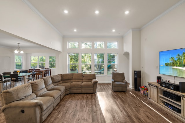 living room featuring ornamental molding, a notable chandelier, hardwood / wood-style floors, and a high ceiling