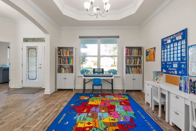 rec room with crown molding, hardwood / wood-style floors, an inviting chandelier, and a tray ceiling