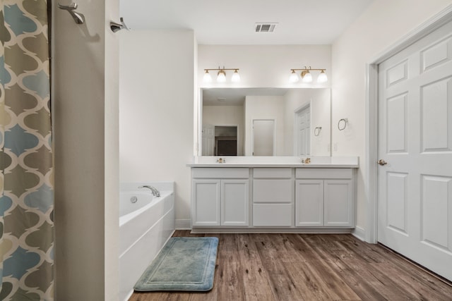 bathroom featuring hardwood / wood-style floors, a washtub, and vanity