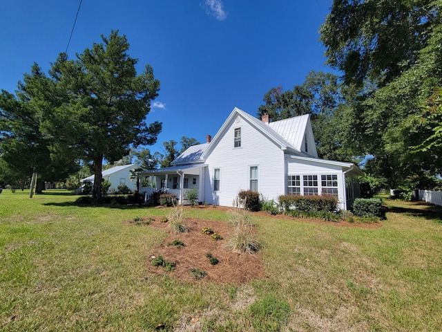 view of side of home featuring a yard and covered porch