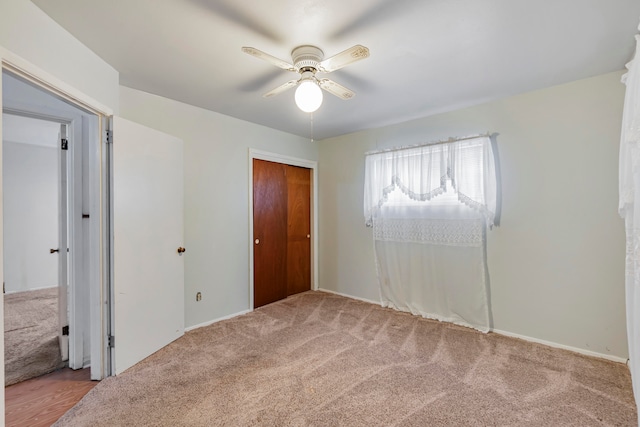 unfurnished bedroom featuring ceiling fan, a closet, and light colored carpet