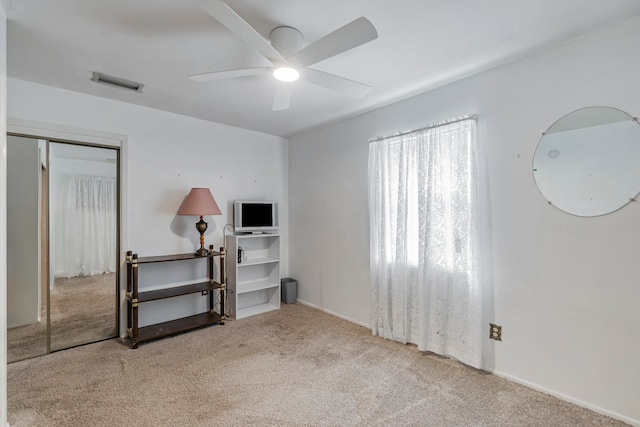 interior space with ceiling fan and light colored carpet