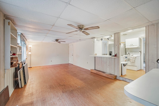 living room with ceiling fan, a drop ceiling, and light hardwood / wood-style floors