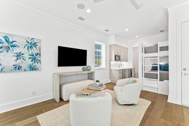 living room featuring wood-type flooring, ornamental molding, and sink