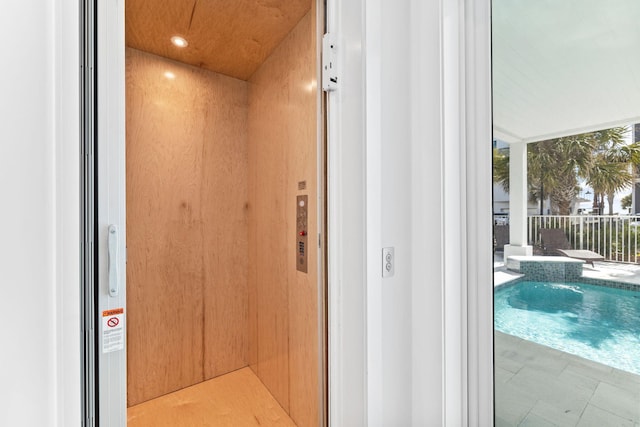 interior space with wood walls, elevator, and a swimming pool