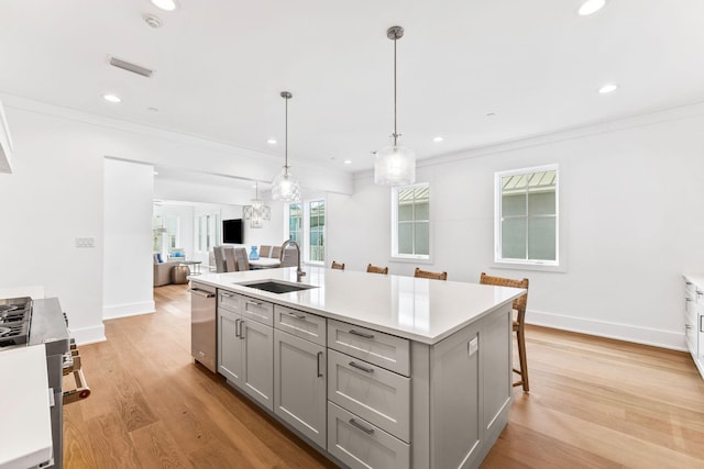 kitchen featuring gray cabinets, light hardwood / wood-style flooring, sink, and a breakfast bar