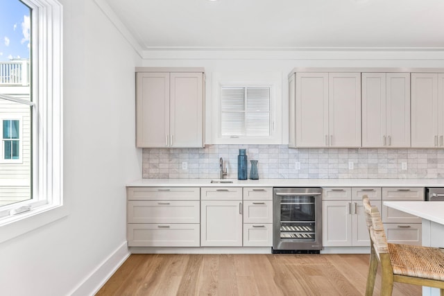 bar featuring decorative backsplash, beverage cooler, and light wood-type flooring