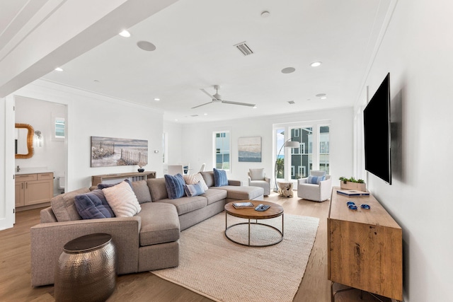 living room featuring ceiling fan, light wood-type flooring, and crown molding