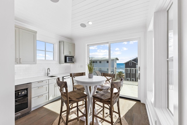 dining room featuring a water view, a wealth of natural light, wine cooler, and dark wood-type flooring