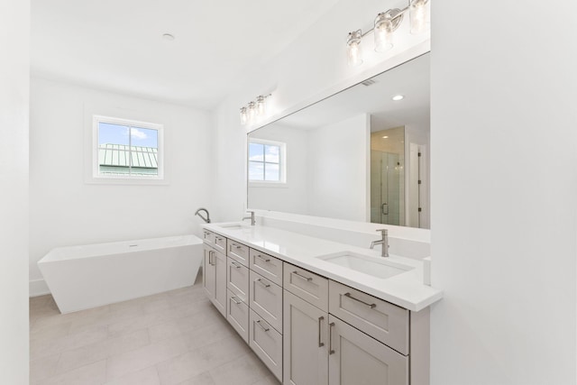 bathroom with independent shower and bath, vanity, and plenty of natural light