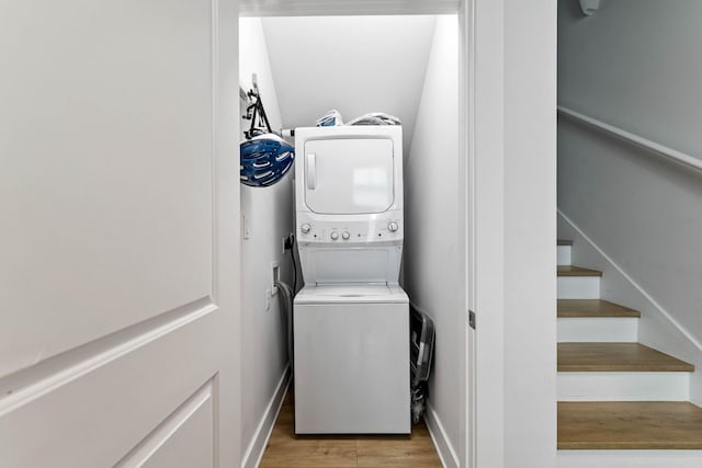 washroom with light hardwood / wood-style flooring and stacked washing maching and dryer