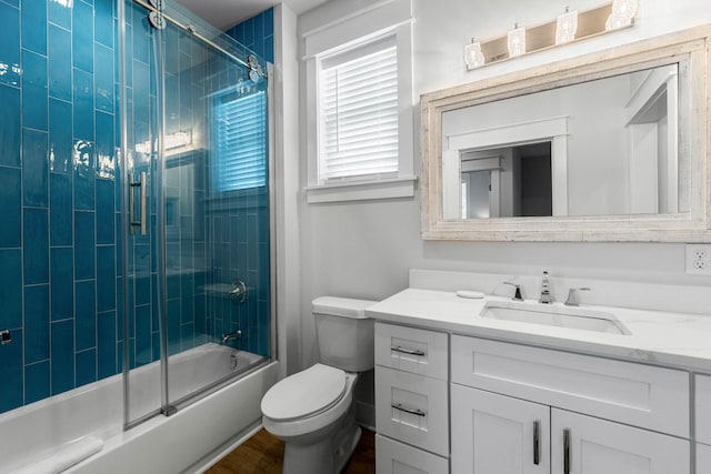 full bathroom featuring bath / shower combo with glass door, vanity, and toilet