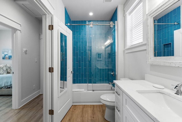 full bathroom featuring vanity, tiled shower / bath combo, hardwood / wood-style floors, and toilet