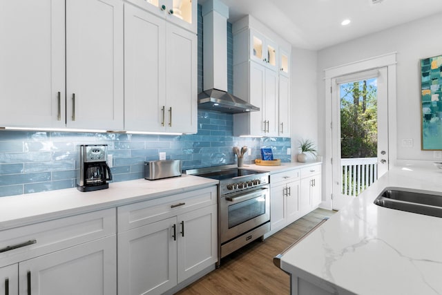 kitchen with white cabinetry, high end stainless steel range, light stone countertops, dark hardwood / wood-style floors, and wall chimney range hood