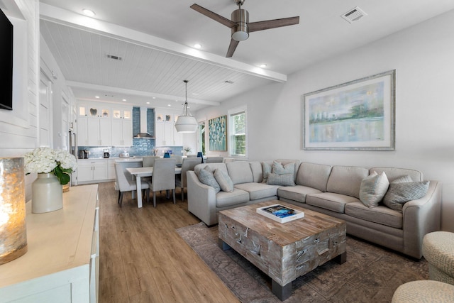 living room featuring wood-type flooring, wood ceiling, beam ceiling, and ceiling fan