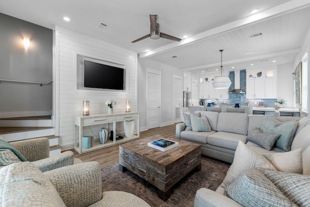 living room featuring beam ceiling, dark hardwood / wood-style flooring, and ceiling fan