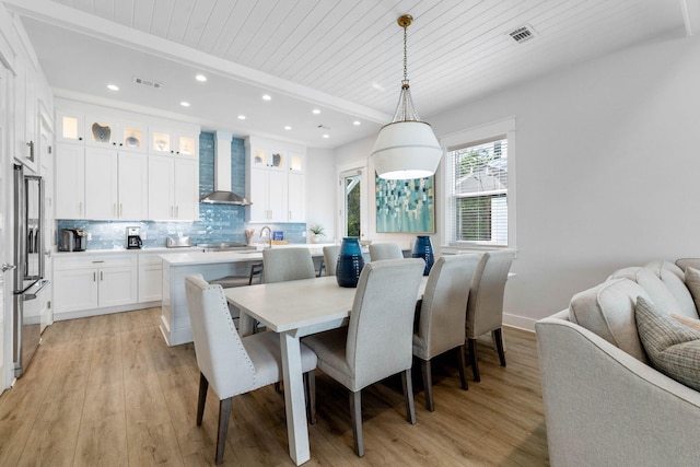 dining area featuring beamed ceiling, wood ceiling, and light hardwood / wood-style floors