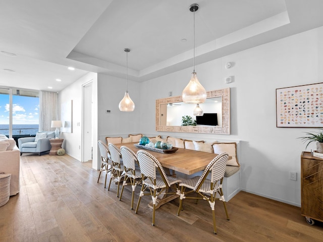 dining room featuring a water view, a raised ceiling, and hardwood / wood-style floors