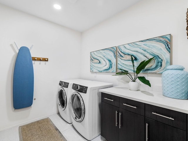 clothes washing area featuring cabinets, washing machine and dryer, and light tile patterned floors