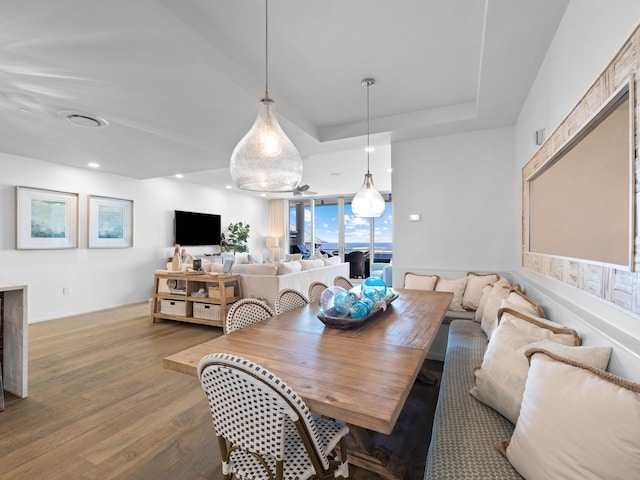 dining space featuring a raised ceiling and wood-type flooring