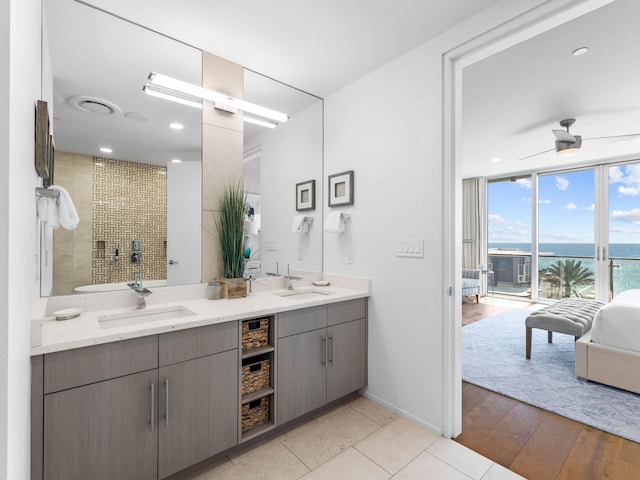 bathroom with vanity, ceiling fan, tiled shower, a water view, and hardwood / wood-style flooring