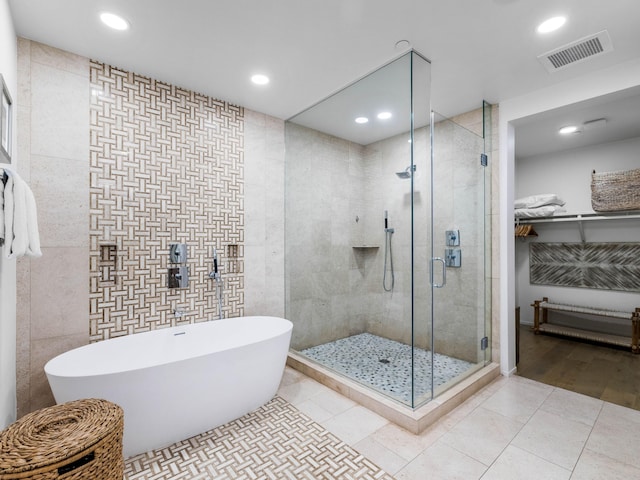 bathroom with tile patterned floors, tile walls, and plus walk in shower