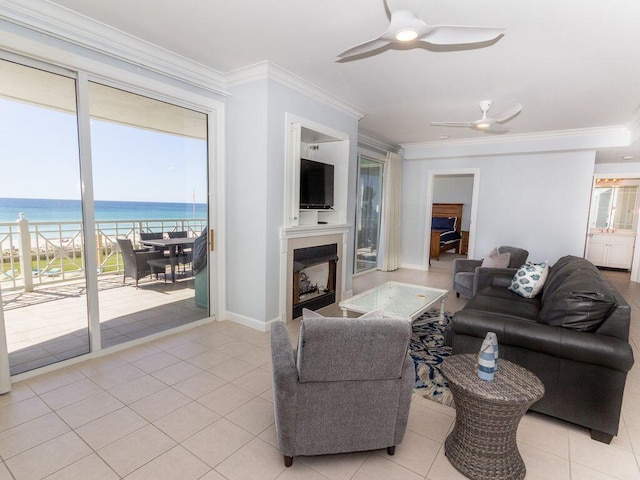 tiled living room featuring ceiling fan, crown molding, and a water view