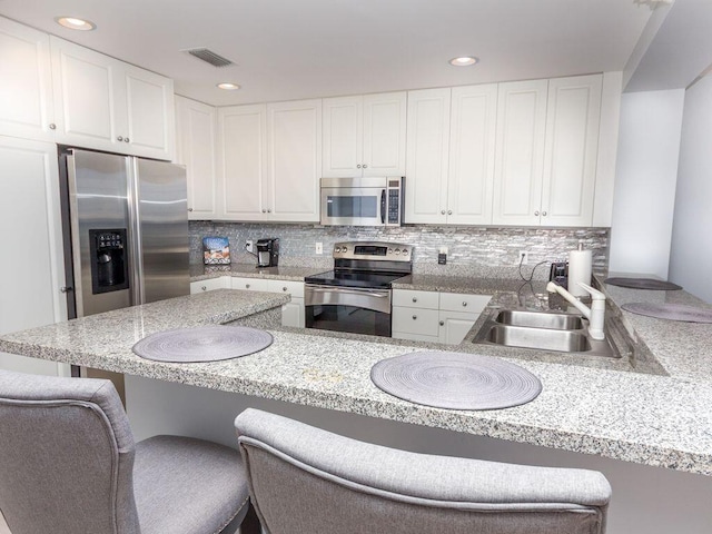 kitchen with a kitchen bar, kitchen peninsula, appliances with stainless steel finishes, and sink