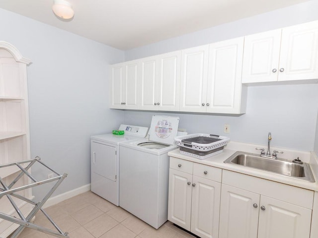 clothes washing area with cabinets, washing machine and dryer, light tile patterned floors, and sink