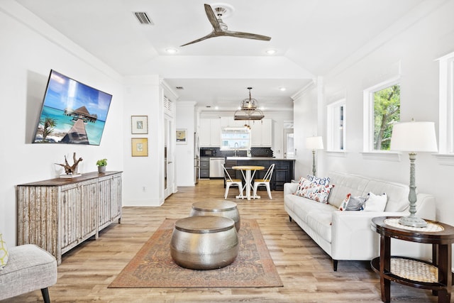 living room with sink, light wood-type flooring, ornamental molding, and lofted ceiling