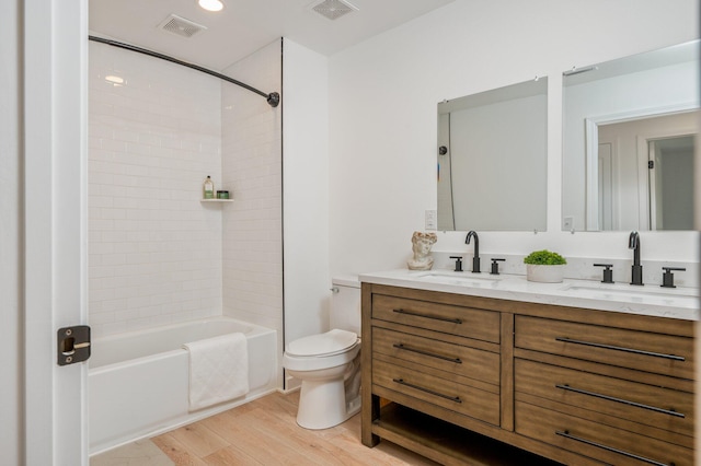 full bathroom featuring vanity, toilet, hardwood / wood-style flooring, and tiled shower / bath