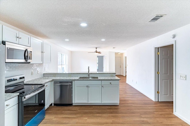 kitchen with light hardwood / wood-style flooring, stainless steel appliances, sink, and white cabinetry