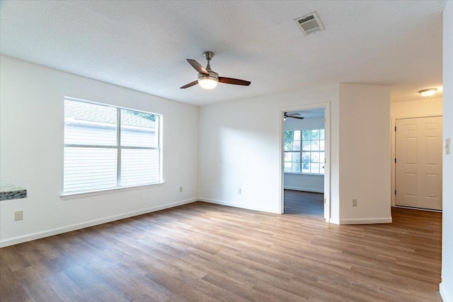 spare room featuring ceiling fan, light hardwood / wood-style flooring, and plenty of natural light