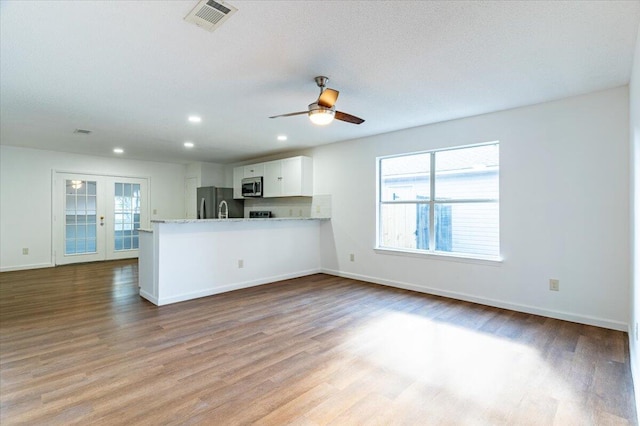 kitchen with ceiling fan, kitchen peninsula, light hardwood / wood-style flooring, white cabinetry, and stainless steel appliances